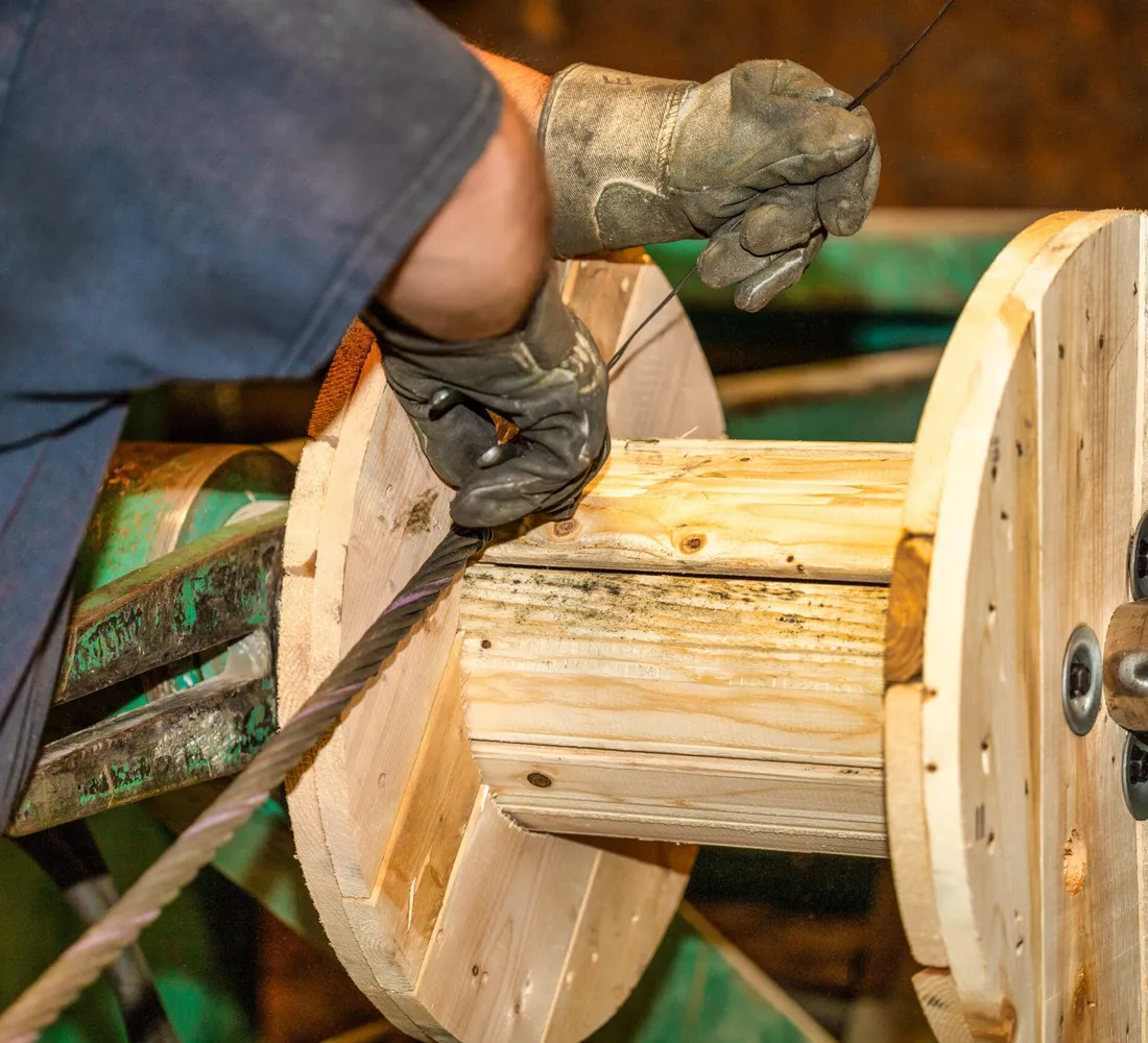 Technician spooling wire rope onto a wooden reel